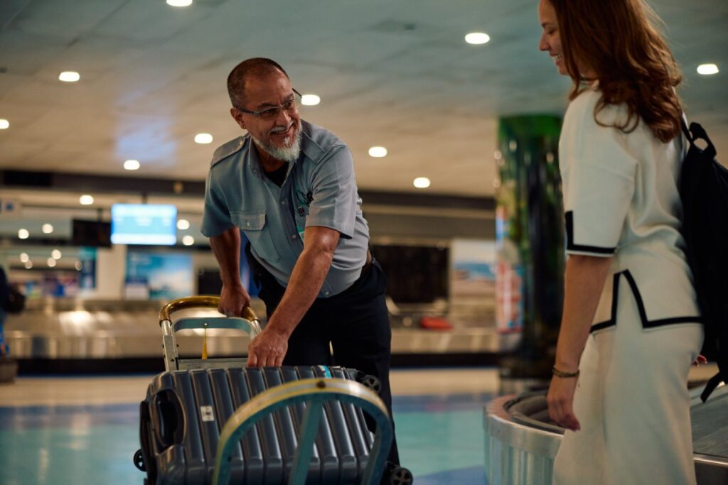 Porter helping a traveler with luggage at baggage claim in San Juan airport