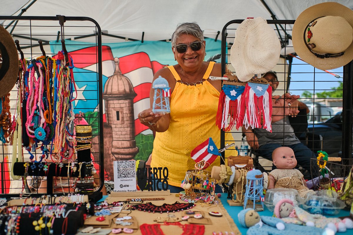 Smiling artisan showing handmade crochet crafts at a market in Toa Baja, Puerto Rico
