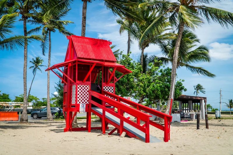 Red lifeguard tower under palm trees at the beach in Toa Baja, Puerto Rico